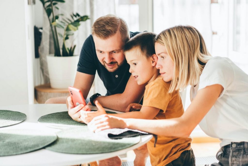 Happy family of three using mobile device together at home with reliable internet connectivity and WiFi service