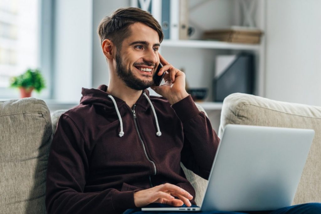Man working from home on laptop while making phone call, demonstrating ElektraFi's reliable internet and phone services