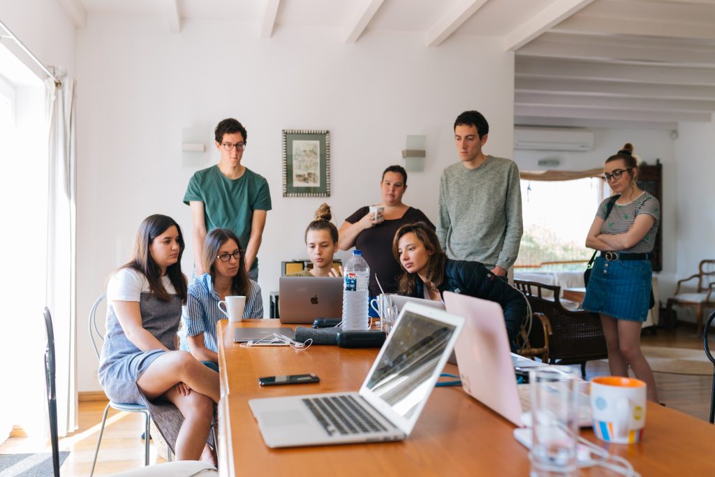 Group of young professionals collaborating around laptops in modern office discussing internet connectivity solutions