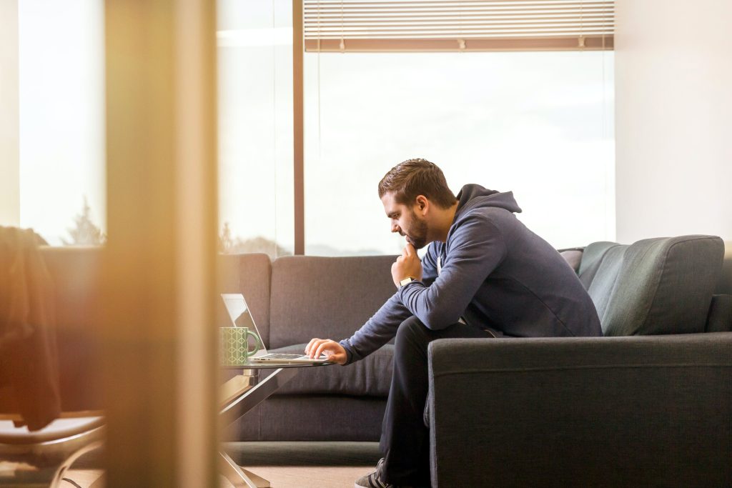 Man using laptop on couch while researching megabit internet speeds and rural internet service options from home