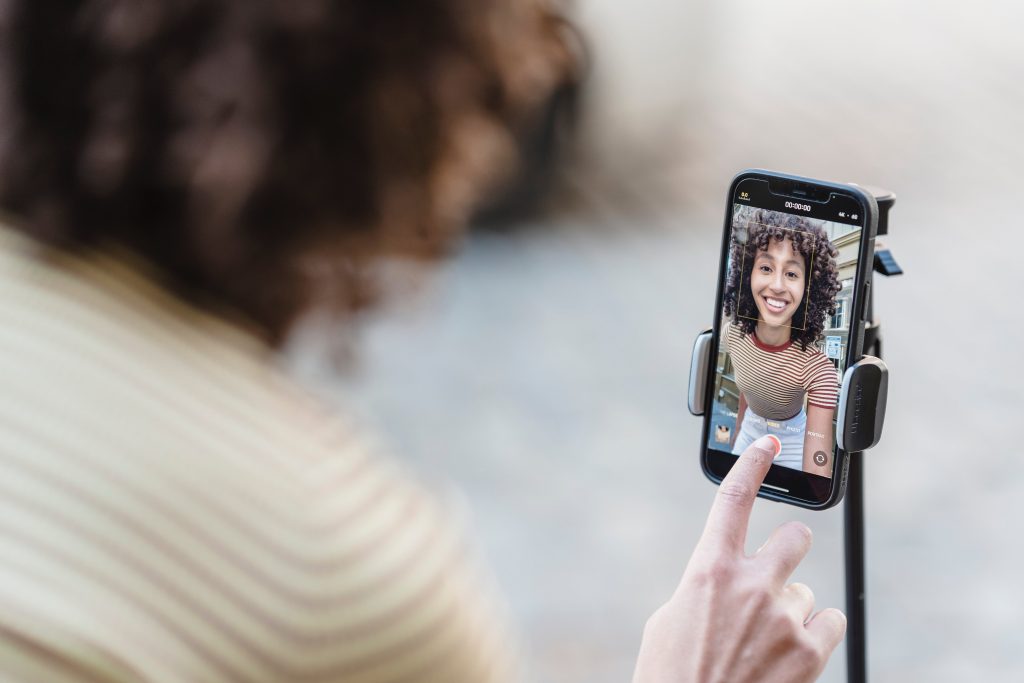 Person using smartphone on tripod for video call or streaming, demonstrating internet speed requirements for online meetings