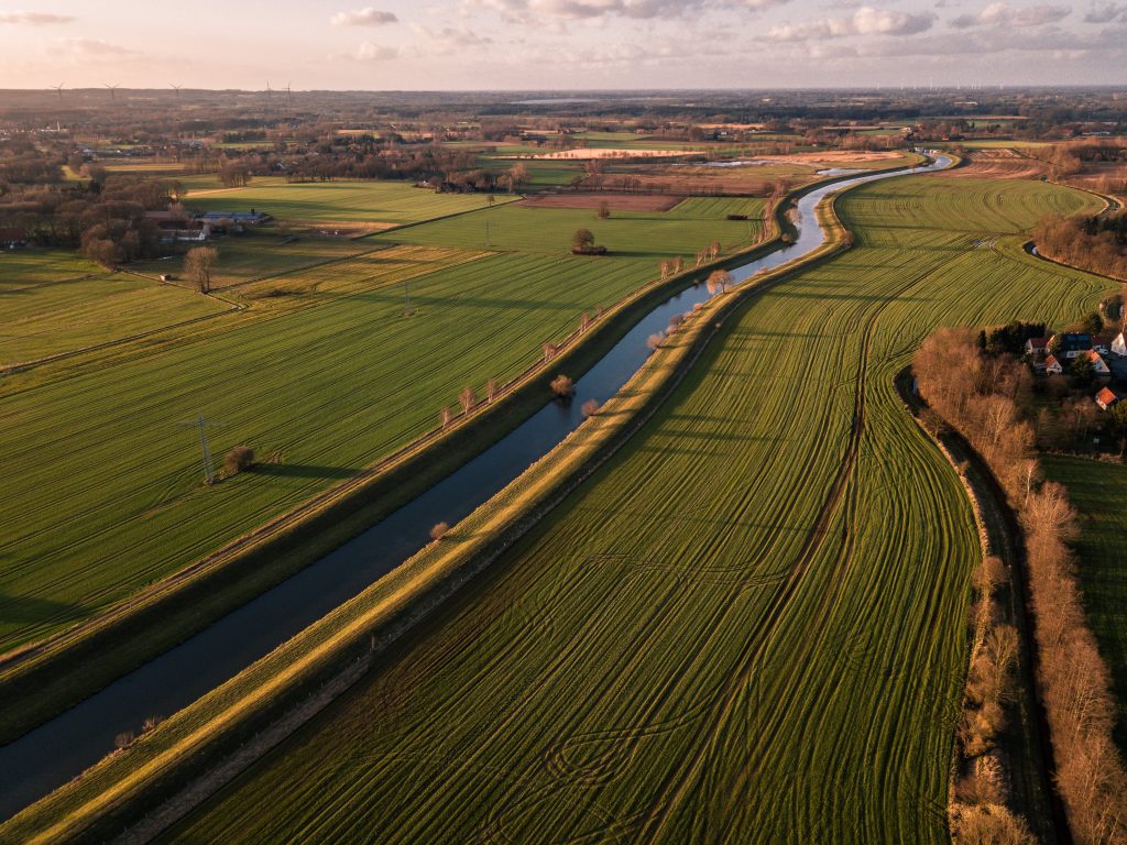 Aerial view of rural farmland with winding river, green fields, and scattered homes needing reliable internet connectivity