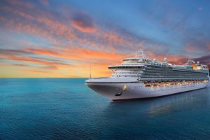 Large cruise ship sailing on calm blue ocean waters under colorful sunset sky - reliable internet connectivity for maritim...